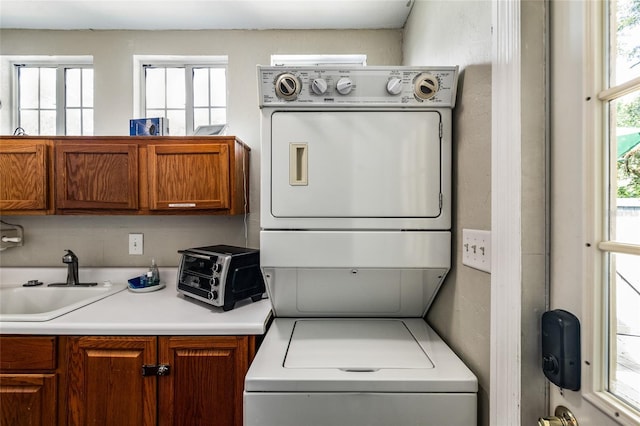 washroom with stacked washer and dryer, plenty of natural light, laundry area, and a sink