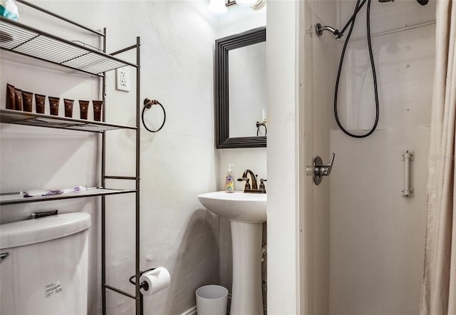 bathroom with toilet, a shower, and a sink