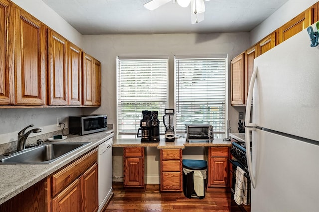 kitchen featuring dark wood finished floors, white appliances, brown cabinets, and a sink