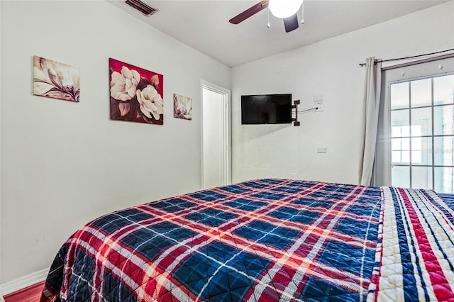 bedroom featuring lofted ceiling, visible vents, ceiling fan, wood finished floors, and baseboards