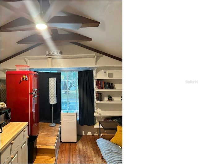 bedroom with lofted ceiling, wood finished floors, and freestanding refrigerator