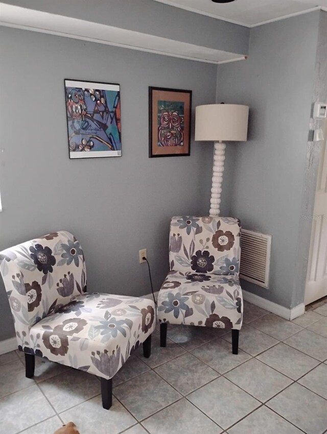 sitting room featuring light tile patterned flooring, baseboards, visible vents, and ornamental molding