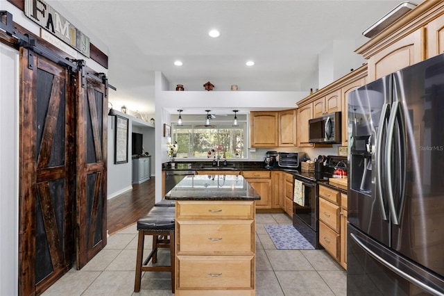 kitchen featuring appliances with stainless steel finishes, a center island, a breakfast bar, sink, and a barn door