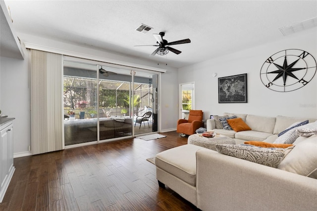 living room featuring dark wood-type flooring, a textured ceiling, and ceiling fan