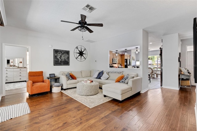 living room with dark wood-type flooring and ceiling fan