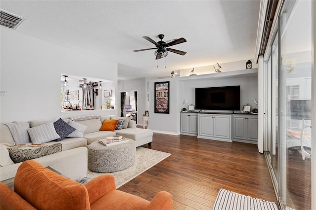 living room with a wealth of natural light, ceiling fan, dark hardwood / wood-style flooring, and a textured ceiling