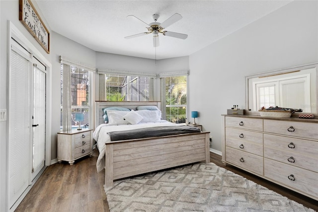 bedroom with a textured ceiling, ceiling fan, and dark hardwood / wood-style floors