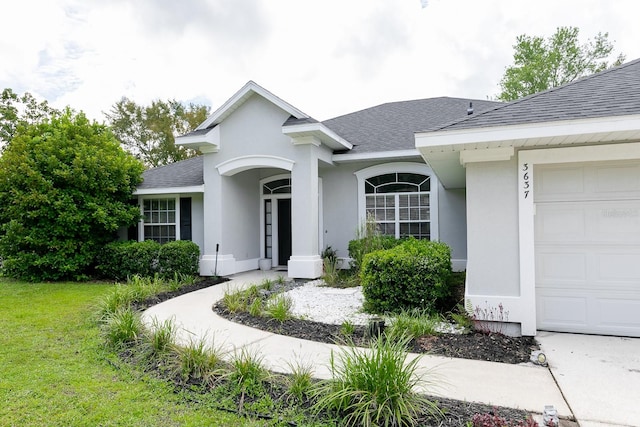 view of exterior entry featuring a garage and a lawn