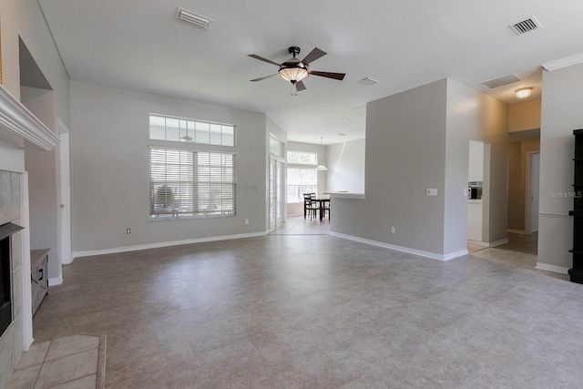 unfurnished living room featuring ceiling fan and a tiled fireplace