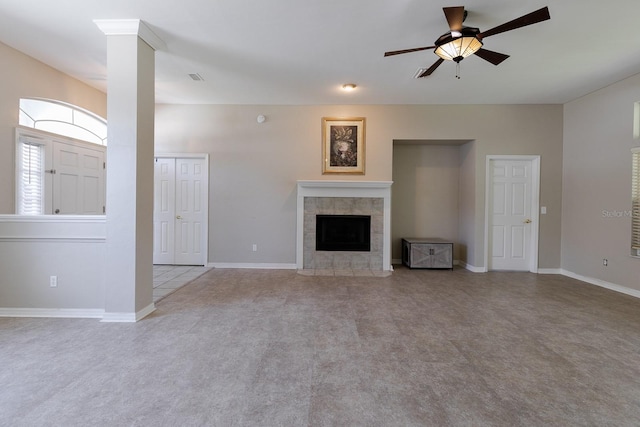 unfurnished living room featuring ceiling fan, light colored carpet, ornate columns, and a tiled fireplace