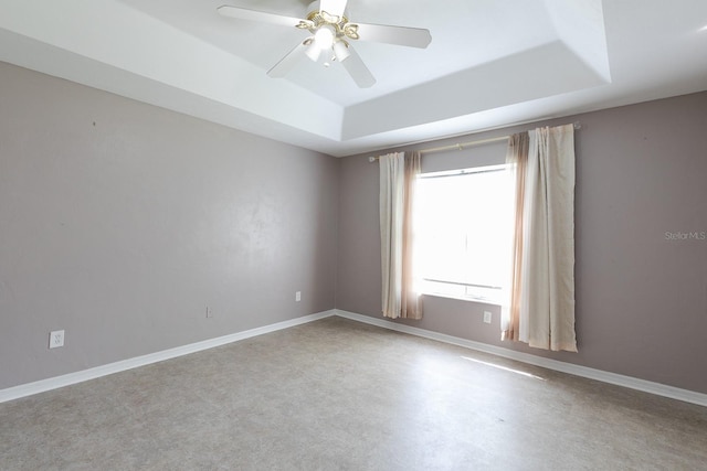 spare room with a tray ceiling and ceiling fan