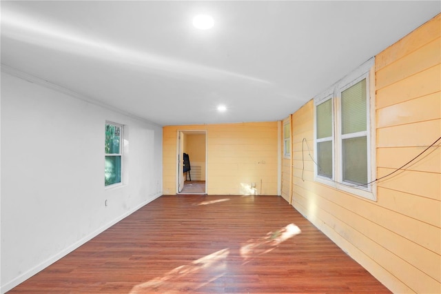 unfurnished room with wood-type flooring, ornamental molding, and wood walls