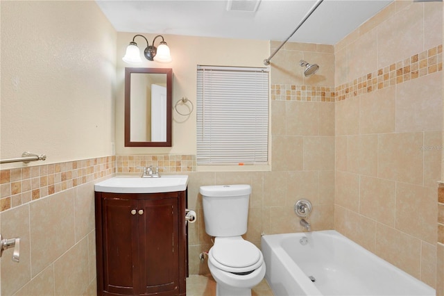 full bathroom with toilet, vanity, tiled shower / bath combo, and tile walls