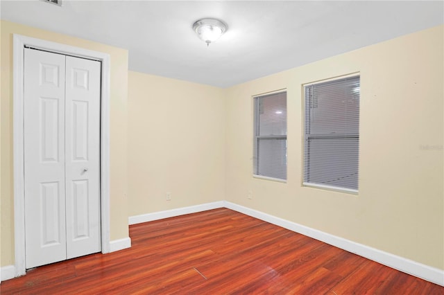 unfurnished bedroom with dark hardwood / wood-style flooring and a closet