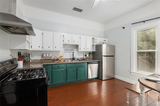 kitchen featuring wall chimney range hood, sink, green cabinets, stainless steel appliances, and white cabinets