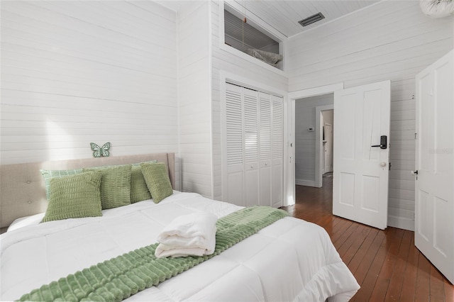 bedroom with a towering ceiling, dark hardwood / wood-style floors, and a closet