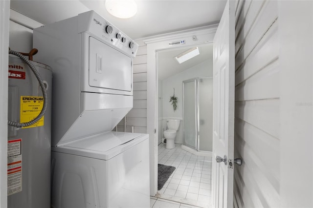 clothes washing area with stacked washer and dryer, electric water heater, and light tile patterned floors