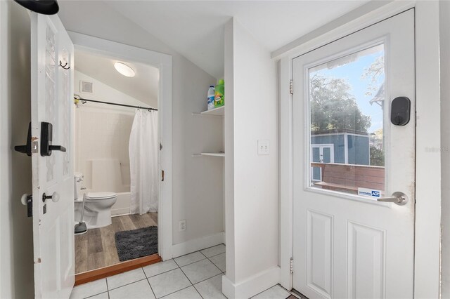 bathroom with tile patterned flooring, lofted ceiling, shower / bathtub combination with curtain, and toilet