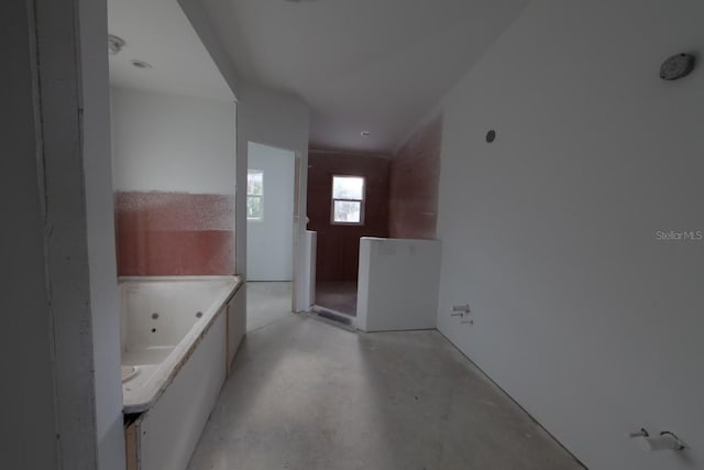 bathroom featuring vanity, a bath, and concrete flooring