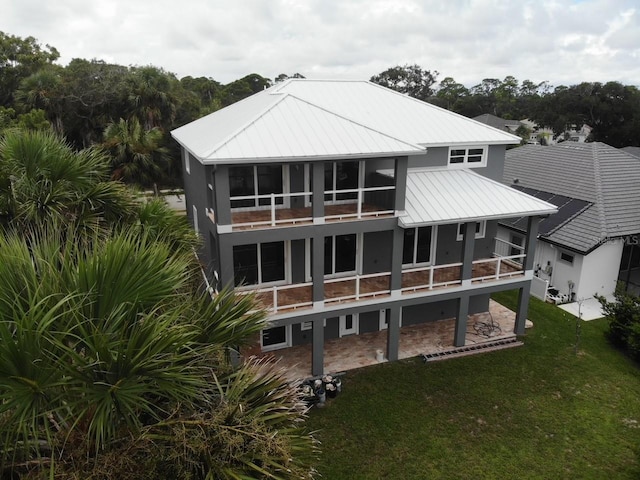 rear view of property with a balcony and a lawn