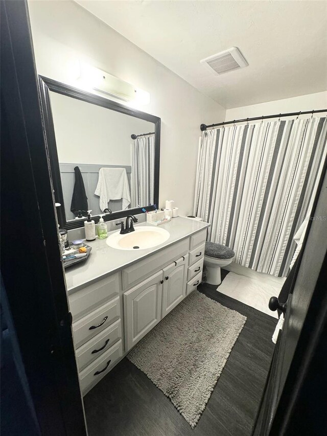 bathroom featuring vanity, toilet, hardwood / wood-style flooring, and curtained shower