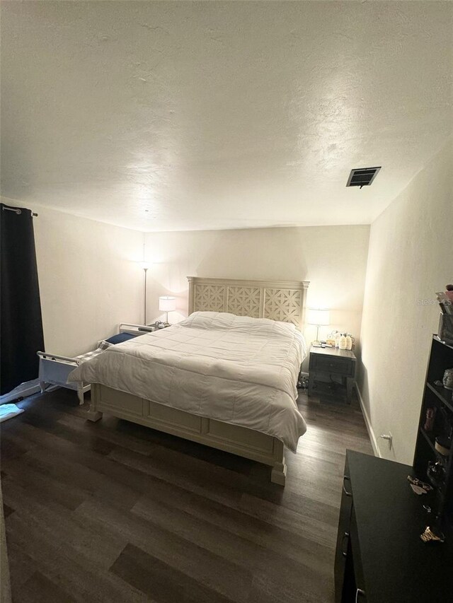 bedroom with dark hardwood / wood-style floors and a textured ceiling