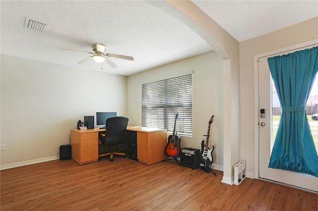 home office with light hardwood / wood-style floors, ceiling fan, and a textured ceiling