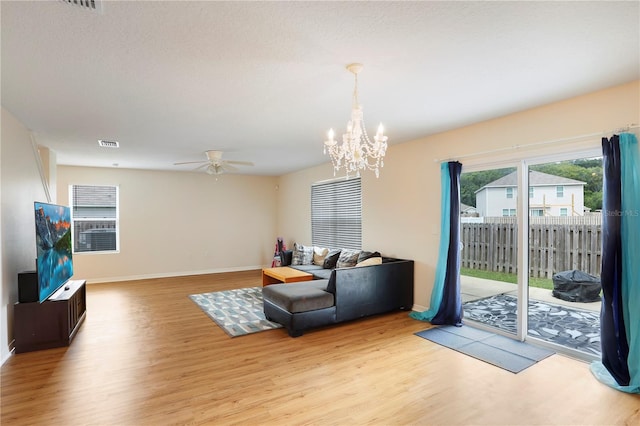 living room with ceiling fan with notable chandelier and light hardwood / wood-style flooring