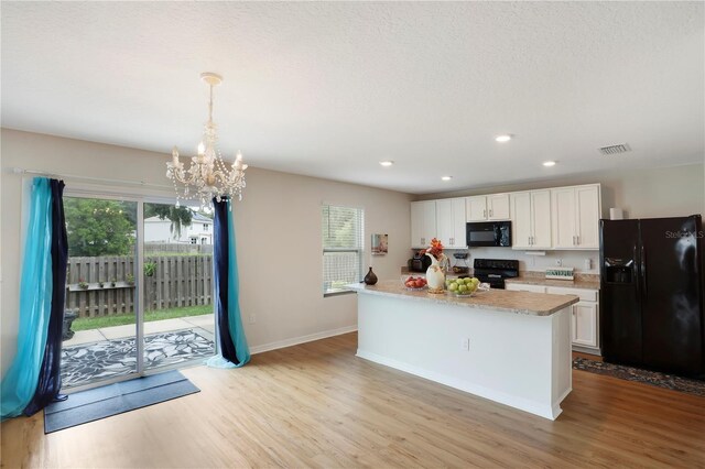 kitchen featuring white cabinets, black appliances, light hardwood / wood-style floors, and decorative light fixtures