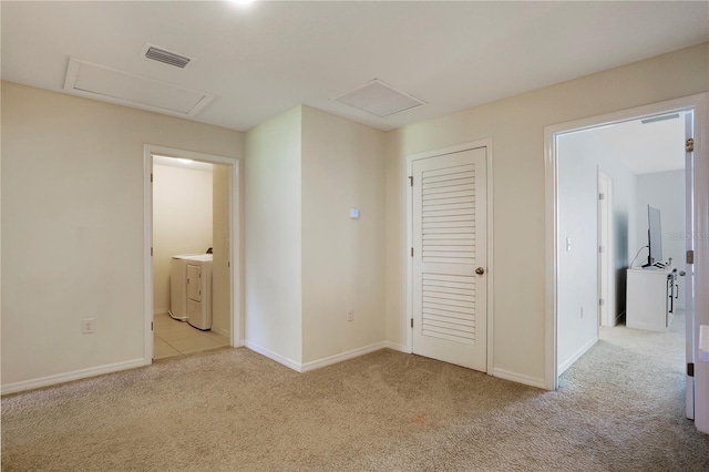 unfurnished bedroom with light carpet, connected bathroom, and washing machine and clothes dryer