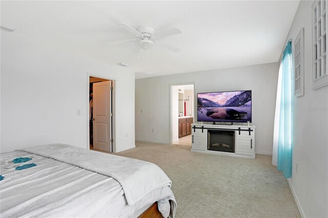 bedroom featuring ceiling fan, ensuite bath, and light carpet