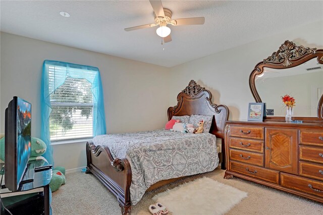 carpeted bedroom with ceiling fan and a textured ceiling