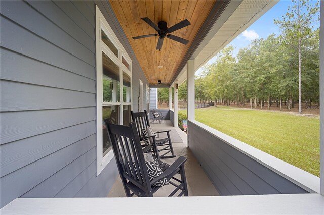 wooden terrace featuring ceiling fan, a lawn, and a porch