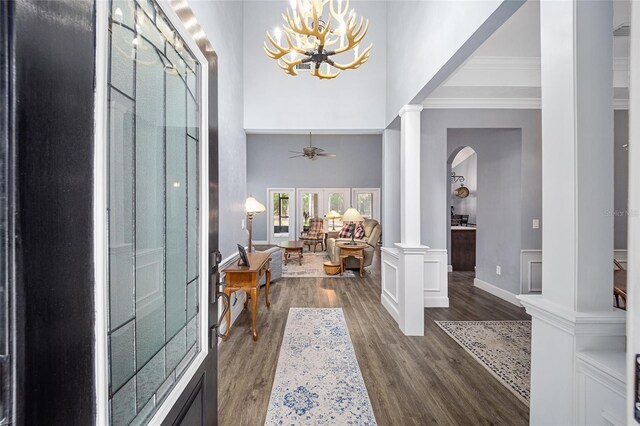 entrance foyer featuring a high ceiling, ceiling fan, dark hardwood / wood-style floors, and decorative columns