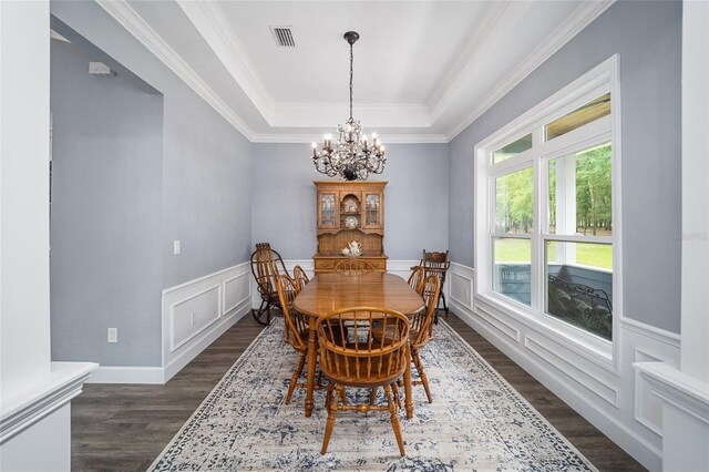 dining area with crown molding, dark hardwood / wood-style floors, a raised ceiling, and a notable chandelier