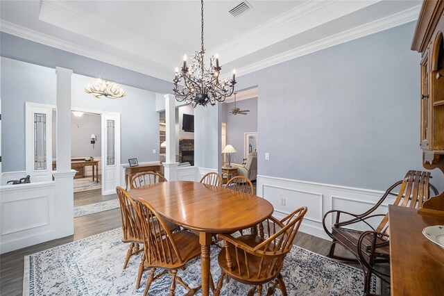 dining room featuring decorative columns, hardwood / wood-style flooring, a chandelier, and ornamental molding