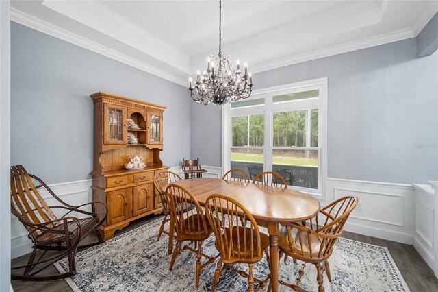 dining space featuring ornamental molding, dark wood-type flooring, a chandelier, and a tray ceiling