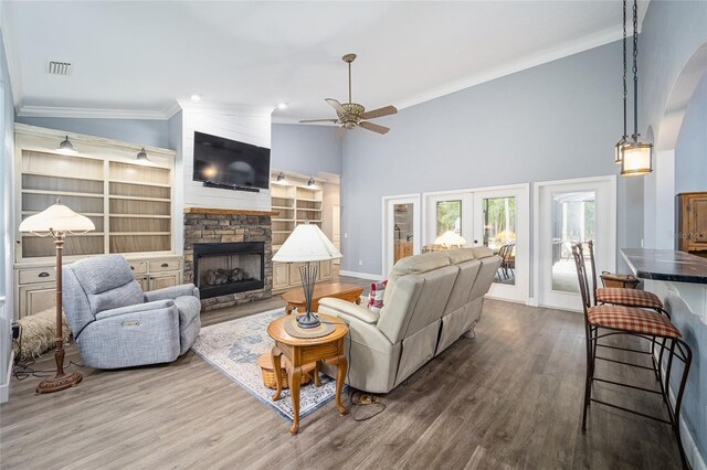 living room featuring a fireplace, crown molding, hardwood / wood-style flooring, and ceiling fan