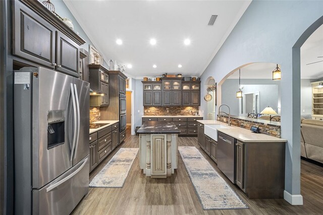 kitchen featuring appliances with stainless steel finishes, an island with sink, and crown molding