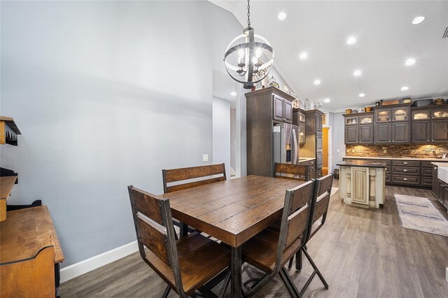 dining space with lofted ceiling, dark hardwood / wood-style floors, and a chandelier