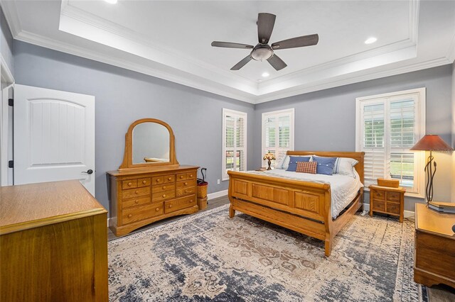 bedroom featuring ornamental molding, hardwood / wood-style flooring, a tray ceiling, and ceiling fan