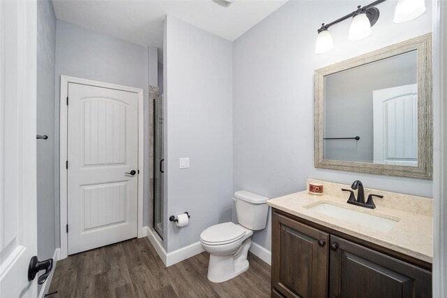 bathroom with vanity, toilet, hardwood / wood-style flooring, and a shower with shower door