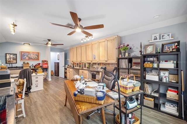 office space featuring built in desk, ceiling fan, and light hardwood / wood-style flooring