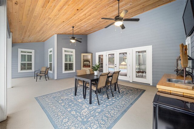 dining area featuring wood ceiling, ceiling fan, sink, concrete flooring, and high vaulted ceiling