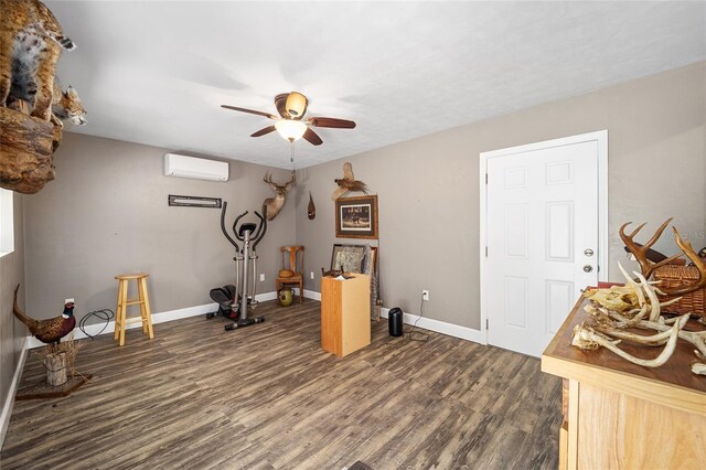 workout area with dark wood-type flooring, ceiling fan, and a wall mounted air conditioner