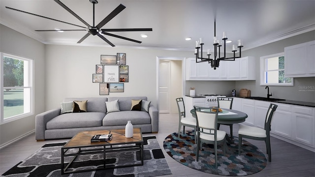 living room featuring hardwood / wood-style floors, ceiling fan with notable chandelier, plenty of natural light, and ornamental molding