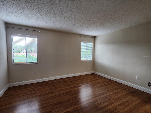 spare room featuring a textured ceiling and dark wood-type flooring