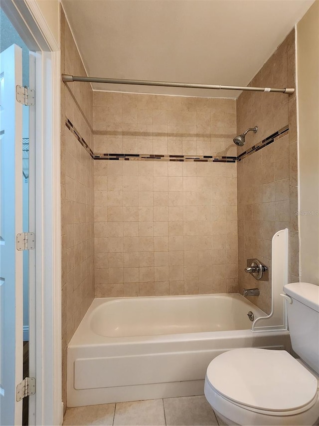 bathroom featuring tile patterned flooring, toilet, and tiled shower / bath combo