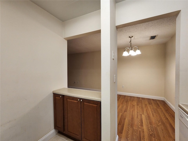 interior space featuring a textured ceiling, pendant lighting, a chandelier, and light hardwood / wood-style floors