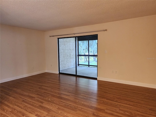 empty room featuring a textured ceiling and dark hardwood / wood-style floors